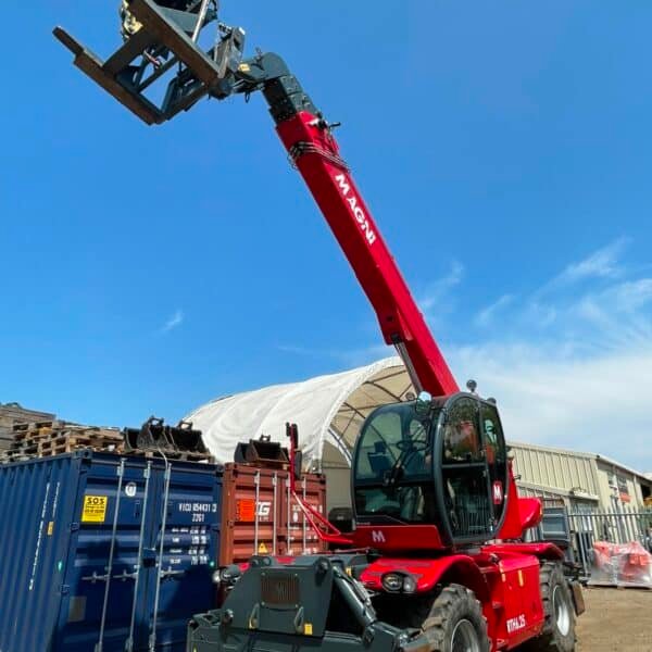 Red telehandler lifting forks beside shipping containers