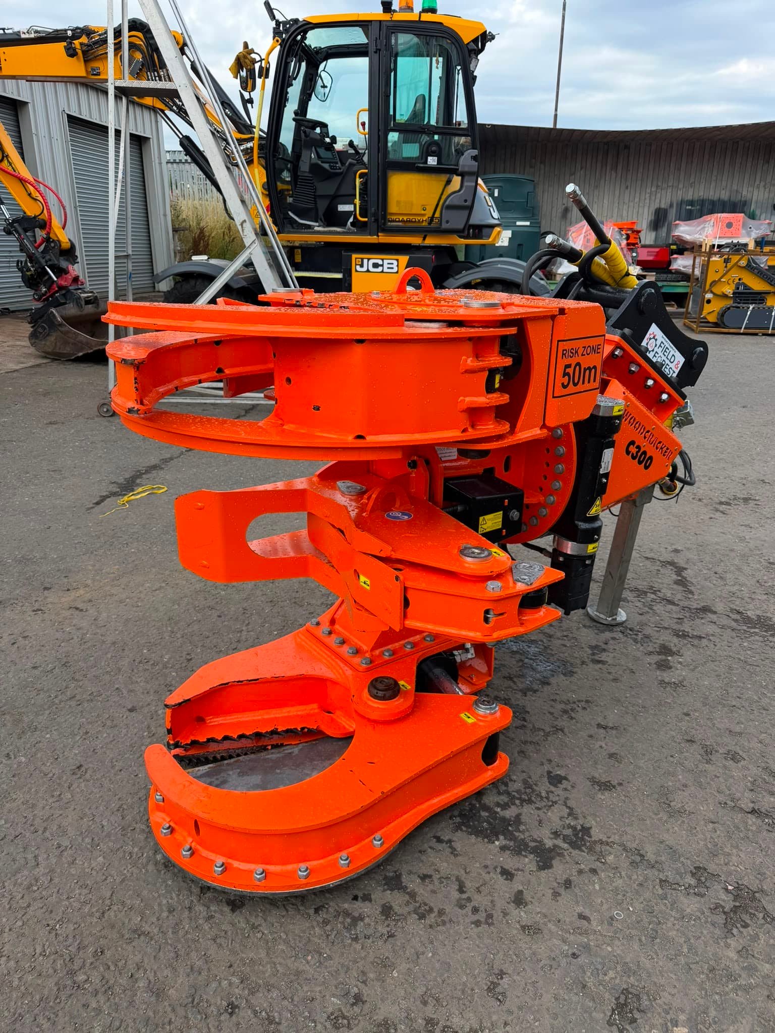 Orange hydraulic tree shear attachment in yard