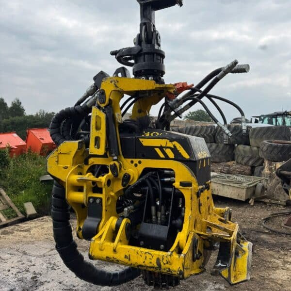 Yellow hydraulic stump grinder attachment on excavator arm