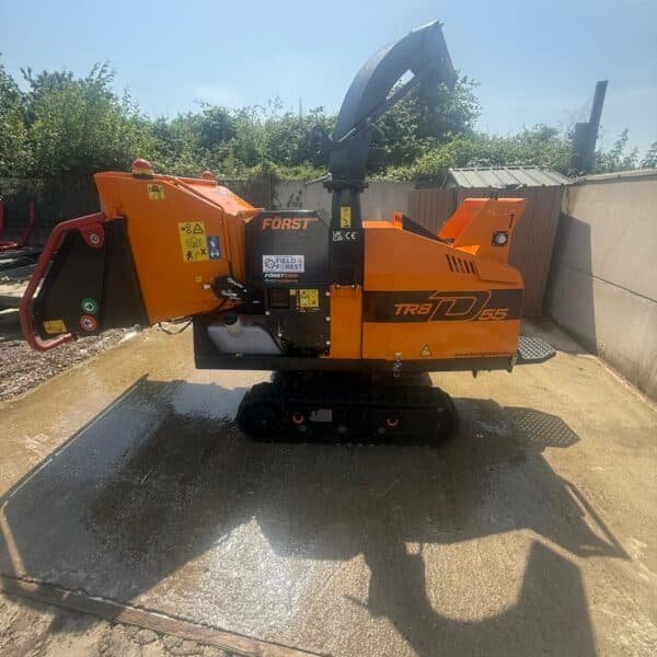 Orange tracked wood chipper on concrete yard