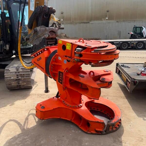 Orange hydraulic excavator attachment in industrial yard