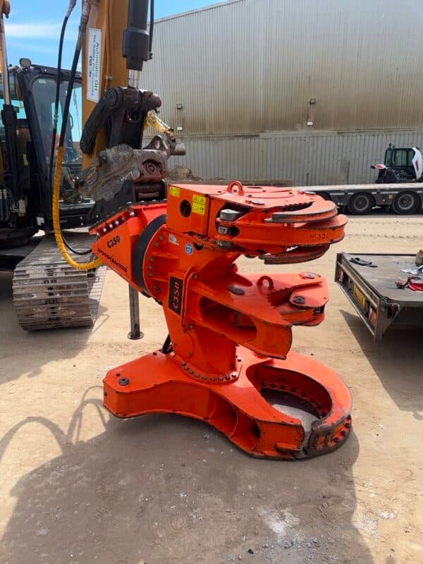 Orange hydraulic excavator attachment in industrial yard