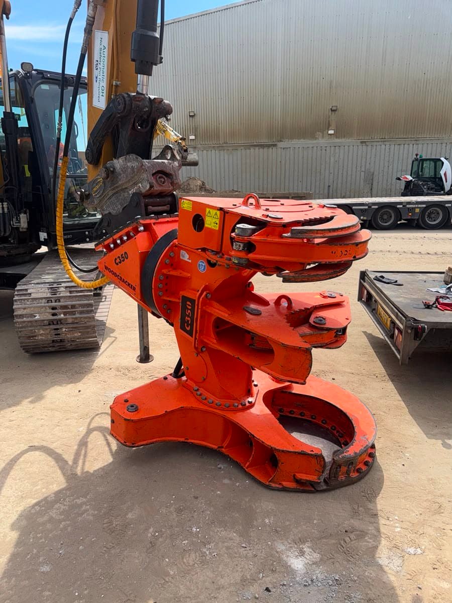 Orange hydraulic excavator attachment in industrial yard