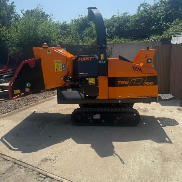 Orange tracked wood chipper on concrete yard