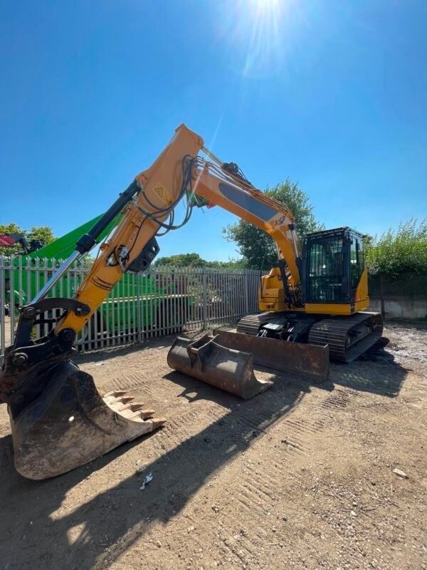 Yellow tracked excavator with buckets in yard