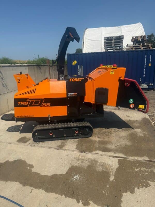 Orange tracked wood chipper in industrial yard
