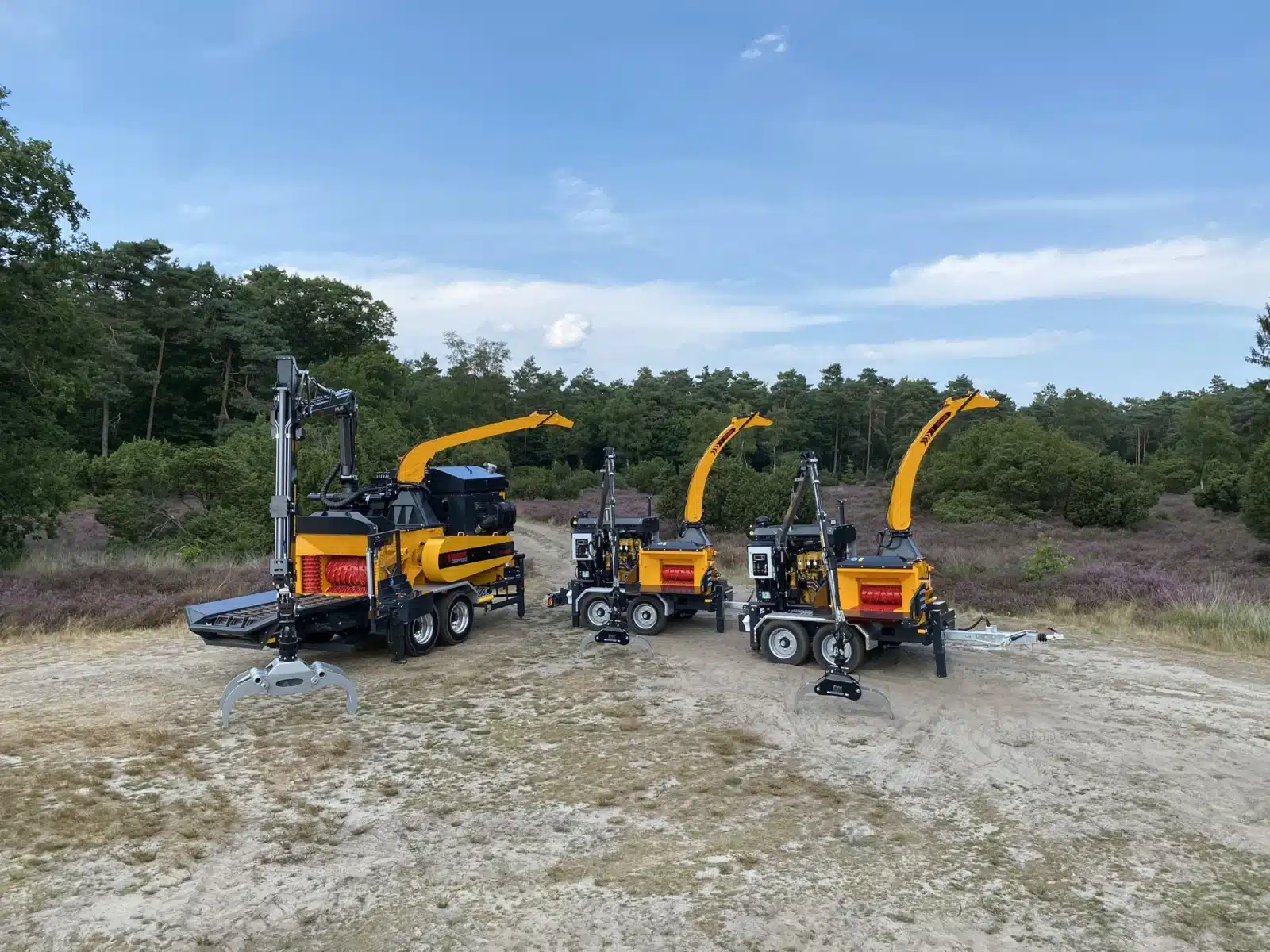 Three Europe Chippers wood chippers lined up at a forest edge