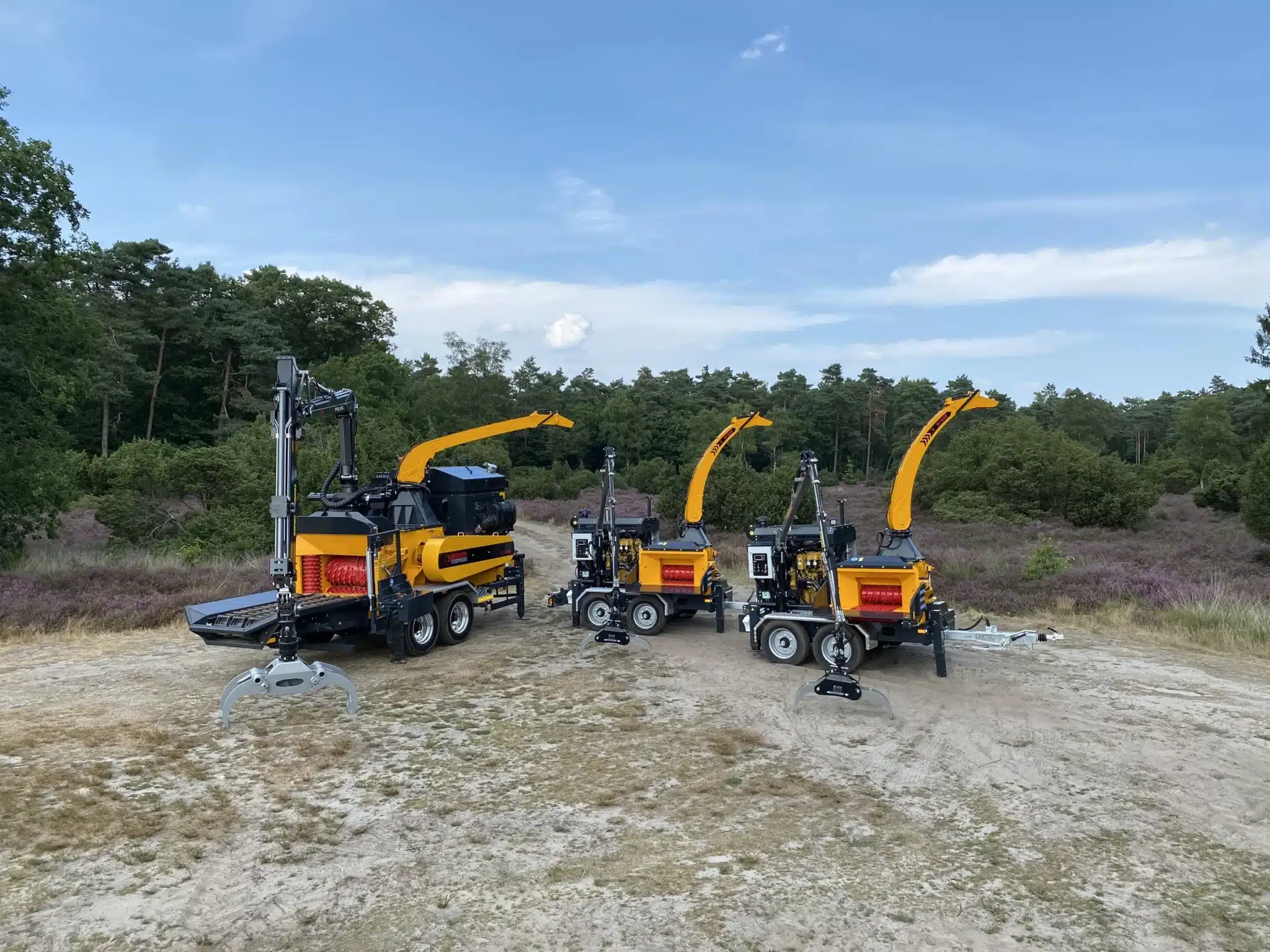 Three Europe Chippers wood chippers lined up at a forest edge
