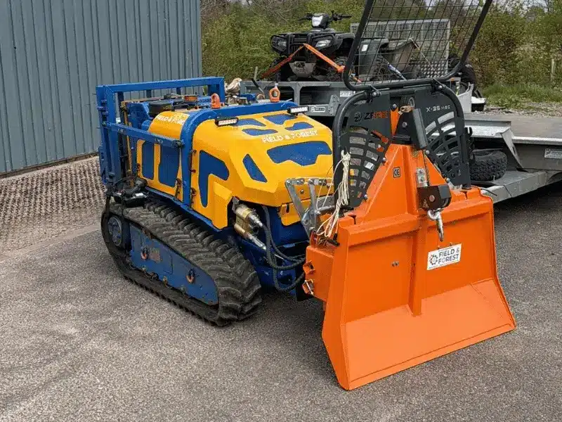 Bomford Flailbot remote‑controlled tracked mower fitted with Field & Forest forestry winch and rear guard parked in yard.