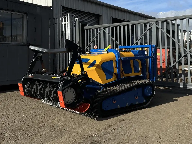 Bomford Flailbot remote‑controlled tracked mower fitted with FlailTec mulcher attachment parked in yard.