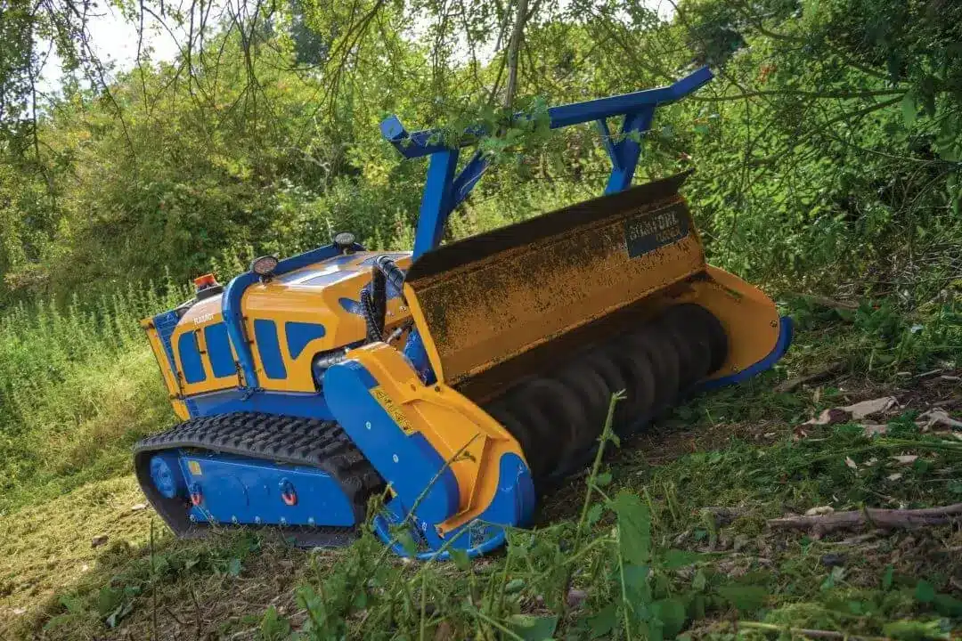 Bomford Flailbot Supreme remote‑controlled tracked forestry mower clearing dense vegetation on a slope.